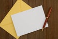 Blank greeting card with yellow envelope and pen on wood Royalty Free Stock Photo