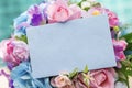 Blank greeting paper blue card on colorful flower bouquet