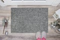 Blank grey doormat before the door in the hall. Mat on wooden floor, with christmas decoration and slippers. Welcome Royalty Free Stock Photo