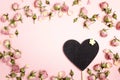 Blank heart-blackboard with small dry roses on pink background. Royalty Free Stock Photo