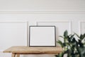 Blank horizontal black picture frame mockup. Old wooden console table. White wall moulding background, trim decor