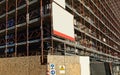 Blank information board hanging on the scaffoldings around the new building under construction. Warning signs at the road side