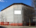 Blank information board on scaffold plastic sheeting covering a facade under refurbishment of a large corner building. Royalty Free Stock Photo