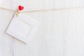 Blank instant photo frame and red heart hanging on the clothesline. Royalty Free Stock Photo