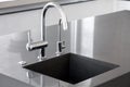 Blank kitchen sink of dark gray marble with chrome tap in a clean kitchen. Royalty Free Stock Photo