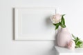 Blank landscape frame mockup on white wall with pink flowers in vase, blank mockup with copy space Royalty Free Stock Photo