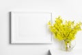 Blank landscape picture frame mockup on white wall with spring yellow flowers Royalty Free Stock Photo