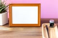 Blank landscape wooden frame beside a small houseplant and calligraphy tools, painting or artwork display mockup