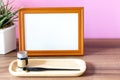 Blank landscape wooden frame beside a small houseplant and calligraphy tools, painting or artwork display mockup