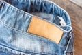 Blank leather jeans label on a blue jeans, wooden background. Royalty Free Stock Photo