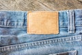 Blank leather jeans label on a blue jeans, wooden background. Royalty Free Stock Photo