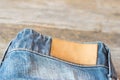 Blank leather label blue jeans on wooden background. Royalty Free Stock Photo