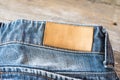 Blank leather label blue jeans on wooden background. Royalty Free Stock Photo