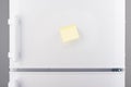 Blank light yellow sticky paper note on white refrigerator