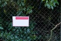 blank medium white sign on metalic fence covered with vegetation