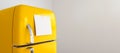 Blank memo note sticker on yellow refrigerator close up. blank paper reminder on retro fridge door