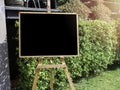 Blank menu chalkboard on wooden easel on green leaves background Royalty Free Stock Photo