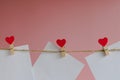 Blank message card attached with a wooden clothespin with a red heart on a rope on a pink background Royalty Free Stock Photo