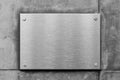 Blank metal sign or nameboard on concrete wall