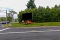 Blank mobile digital road sign on the grass by a street intersection