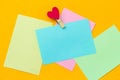 multicolored paper notes with cloth pin decorated with red heart on a vibrant yellow background Royalty Free Stock Photo