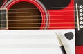 Blank music notebook page with copy-space, on red guitar with six strings. With pen and black guitar pick. Musical education