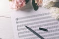 Blank music notes sheet with flowers and pen on white wooden table Royalty Free Stock Photo