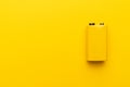 Blank nine-volt battery on yellow background with copy space