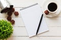 Blank note pad, pen, cookies, green plant and a cup of coffee on white wooden table Royalty Free Stock Photo