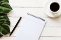 Blank note pad, pen and a cup of coffee on white wooden table Royalty Free Stock Photo