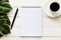 Blank note pad, pen and a cup of coffee on white wooden table Royalty Free Stock Photo