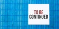 Blank note pad with text TO BE CONTINUED on blue wooden background Royalty Free Stock Photo