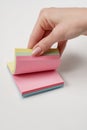 Blank note paper set of different colours. Sticky notes collection on gray background. Female hand leafing through colored paper Royalty Free Stock Photo