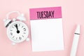 The Blank note paper for Tuesday and pen with alarm clock on pink color background for your text or message Royalty Free Stock Photo