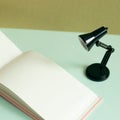 Blank notebook and black desk lamp on sky blue desk