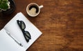 Blank notebook with black glasses, pen and cup of coffee are on top of wood table. Flat lay Royalty Free Stock Photo