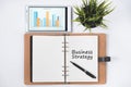 Blank notebook with BUSINESS STRATEGY word and digital tablet with business chart on white flat lay Royalty Free Stock Photo