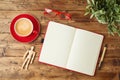 Blank notebook, coffee cup, plant and eyeglassess on wooden office desk. Home workplace, freelancer and blogger concept