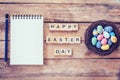 Blank notebook, Colorful easter egg in the nest and wood text for Happy Easter Day on wood background with space