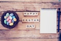 Blank notebook, Colorful easter egg in the nest and wood text for Happy Easter Day on wood background with space
