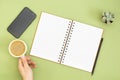 Blank notebook with empty page, pencil and hand holding a coffee cup. Table top, work space on green background. Creative flat lay Royalty Free Stock Photo