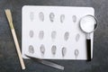 Top view of fingerprints as a criminal evidence, detective`s special tools for investigation on the grey table Royalty Free Stock Photo