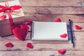 Blank notebook and gift box with red heart on wood background. Royalty Free Stock Photo