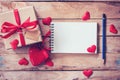 Blank notebook and gift box with red heart on wood background. Royalty Free Stock Photo