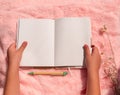 Blank notebook mockup in hands on pink faux fur. Coral fluffy feminine fabric background top view. Female blog template