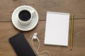 Blank notebook next to a pencil, a cup of coffee and phone with headphones. Royalty Free Stock Photo