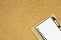 A blank notebook page and pen on cork board, Top view with copy space. Royalty Free Stock Photo