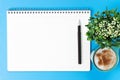 Blank notebook with a pen and a cup of coffee on blue background, top view. Royalty Free Stock Photo