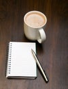 Blank notebook, pen and cup of coffee on wooden brown background Royalty Free Stock Photo