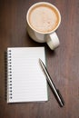 Blank notebook, pen and cup of coffee on wooden brown background Royalty Free Stock Photo